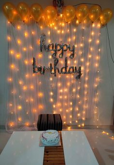 a birthday cake sitting on top of a table in front of a backdrop with balloons