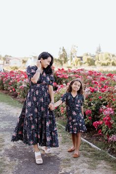 Complete your dress collection with this show-stopping Sienna Dress. This gorgeous black dress features a romantic, pink floral pattern that perfectly contrasts fun white polka dots, allowing you to embrace every side of yourself. Plus, it's available in a mini size, so you and your daughter can match for a picture-perfect moment you'll never forget STYLE INFO & CARE Tiered Skirt Smocked Waist Fully Lined 100%  Polyester  Machine Washable in cold water, or for best results dry clean Black Short Sleeve Dress For Garden Party, Feminine Black Dress For Casual Occasions, Flowy Black Maxi Dress In Feminine Style, Black Flowy Feminine Maxi Dress, Fitted Black Floral Maxi Dress, Black V-neck Midi Dress For Garden Party, Black Floral Maxi Dress For Garden Party, Black Floral Print Dress For Wedding, Feminine Black Short Sleeve Dress