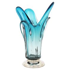 a blue glass vase sitting on top of a metal stand with three curved shapes in it