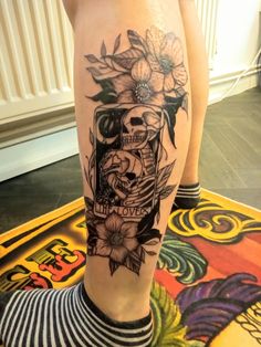 a woman's leg with a skull and flowers on it