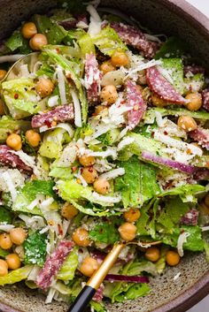 a salad with lettuce, chickpeas and parmesan cheese in a bowl