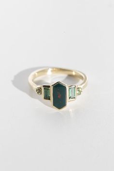 Art deco inspired ring with bloodstone and green tourmaline. Bloodstone is inlaid into the elongated hexagon, measuring 9.5mm x 5mm. Accent tourmalines are approximately .30 total carat worth. Millimeter measurement from end to end is 15mm. 14k yellow gold setting, and the band is 1.75mm thick. Please leave a note at c Horizontal Gemstone Ring, Artist Engagement Rings, Art Deco Ring Emerald, Unique Black Rings, Bloodstone Ring Engagement, 5 Stone Engagement Rings, Green Garnet Ring, Bloodstone Engagement Ring, Emerald Ring Vintage Gold