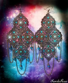 These exotic chandelier earrings are made with filigree pendants decorated with Teal & Fuchsia Swarovski rhinestones. Draped chains and Teal blue crystal beads hang from the design. There are 72 hand set Swarovski and Preciosa Rhinestones on this pair!  These can be worn everyday comfortably because they are lightweight for their size!  They're available with Posts, Clip-Ons or French Wires. Metal Finishes Available: -Bronze (as pictured) -Silver -7" Long (including piercing) x 3" Wide -0.4 oz.. Affordable Blue Bohemian Chandelier Earrings, Bohemian Jeweled Crystal Earrings For Party, Bohemian Turquoise Chandelier Earrings For Party, Turquoise Bohemian Chandelier Earrings For Party, Bohemian Crystal Earrings For Party, Bohemian Teardrop Jeweled Jewelry, Ornate Chandelier Earrings For Party, Ornate Chandelier Earrings For Festivals, Jeweled Dangle Chandelier Earrings