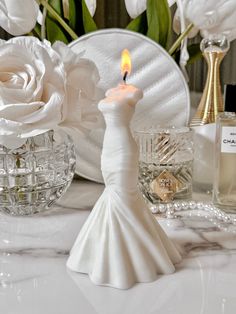 a candle that is sitting on a table next to some flowers and other things in the background