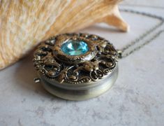 "Turquoise rivoli crystal music box pendant. This round music box pendant is inspired by the gorgeous music box pendants of era's gone by. Music box is pill box size, please look at the dimensions for exact size. A perfect round bronze locket has been adorned with layers of bronze filigree and Turquoise Rivoli Crystal in the center. The bronze filigree layers have been sealed in a clear resin to give a glass like finish and preserve the beauty of this musical pendant. The music box winds from a Music Box Necklace, Music Box Locket, Saint Helens, Music Box Jewelry, Box Necklace, Turquoise Crystal, Black Gift Boxes, Necklace Box, Unique Jewelry Designs