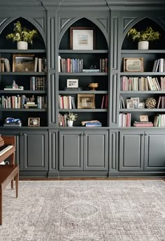 a living room filled with lots of bookshelves next to a piano in front of a window