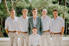 a group of men standing next to each other in white shirts and khakis