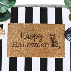 a door mat with the words happy halloween written on it next to potted plants