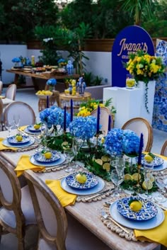 a table set up with blue and yellow plates, napkins and place settings for an event