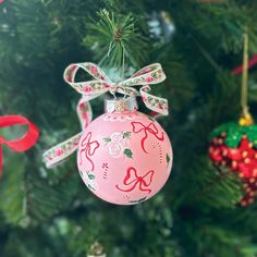 a pink ornament hanging from a christmas tree with red and green ornaments on it