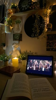 an open book sitting on top of a table next to a laptop computer and candle