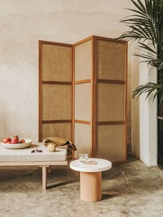 a room divider sitting next to a table with fruit on it and a bowl of strawberries