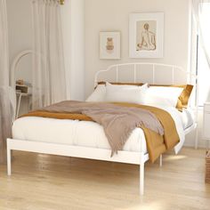 a white bed sitting in a bedroom on top of a hard wood floor next to a window