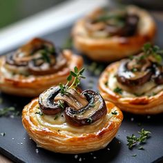 small pastries with mushrooms and herbs on a black tray