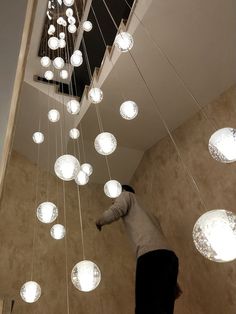 a person reaching up to light bulbs suspended from the ceiling