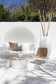 an outdoor living room with white furniture and trees in the backgroung area