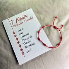 a red string bracelet on top of a white paper with the words 7 knots written in it