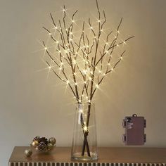 a vase filled with branches sitting on top of a wooden table next to a christmas ornament