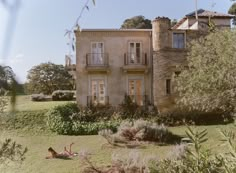 an old house with trees and bushes surrounding it