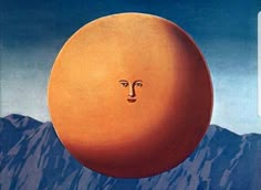 an orange with a face drawn on it in front of mountains and blue sky above