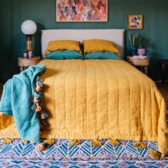 a bedroom with green walls and yellow bedspread on top of a colorful rug