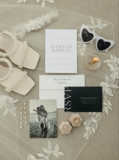 the wedding stationery is laid out with shoes, sunglasses and brochure