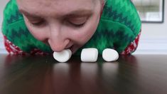 a woman with her eyes closed while chewing on marshmallows in front of her