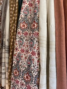 an assortment of scarves hanging on a rack