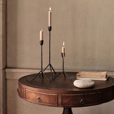 three candles are placed on top of a table next to some books and a rock