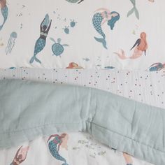 an unmade bed with mermaids and sea creatures on the sheets, along with a pillow case