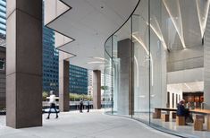 people are walking through an empty building with glass walls