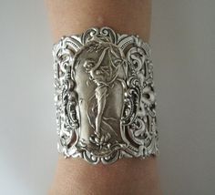 "Art Nouveau Bracelet This beautiful silver plated cuff bracelet has a silver plated art nouveau maiden, silver plated chain and lobster clasp. 2.75\" at the widest part. 7\" long adjustable to 9\" long." Victorian Hallmarked Cuff Bracelet As A Gift, Handmade Victorian Cuff Bracelet For Wedding, Victorian Cuff Bracelet With Intricate Design As Gift, Victorian Style Silver Bracelets As Gift, Handmade Victorian Sterling Silver Bracelets, Handmade Victorian Sterling Silver Bracelet, Art Deco Bracelets With Intricate Design As Gift, Art Deco Handmade Bracelets As Gift, Unique Antique Silver Bracelet For Wedding