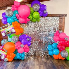 an assortment of balloons and disco balls are arranged on the floor in front of a backdrop