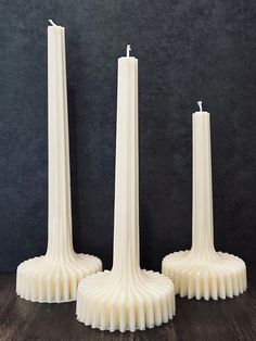 three white candles sitting on top of a wooden table