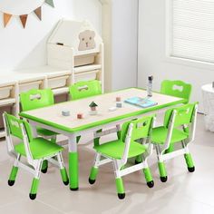 a child's table and chairs in a white room with green trimmings