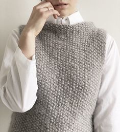 a woman wearing a knitted vest and white shirt