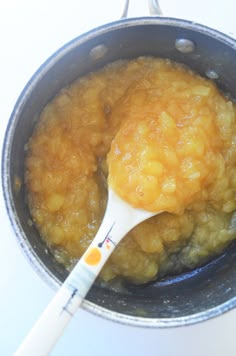 a spoon in a pot filled with food on top of a table next to a white counter