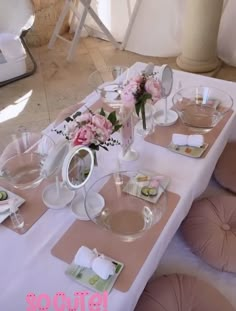 the table is set with pink flowers and plates