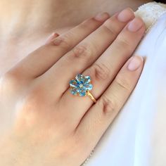 Flora 14K Solid Gold Diamond Natural Topaz Blue Gemstone Blossom Ring *Metal: 14K Solid Gold (Yellow, White, or Rose) *Gemstone:      - **Topaz     - Cut: Pear-Cut      - Size: 6 Pieces 4 * 6 mm     - Total Carat Weight (CTW): 3.00     - Ring Size: Available in various sizes, custom sizes upon request *Diamonds:    - Color: Gold   - Clarity: VS    - Total Carat Weight (CTW): 0.02 Flora 14K Solid Gold Diamond Natural Topaz Blue Gemstone Blossom Ring is an exquisite embodiment of elegance and brilliance. The ring features radiant natural blue topaz gemstones, meticulously arranged in a blossoming flower design. The vibrant blue hue of the topaz stones reflects tranquility, loyalty, and love, making this ring an ideal symbol for cherished moments and lasting relationships. Set in 14K solid go Flower Shaped Birthstone Ring For Anniversary, Blue Topaz Cluster Ring For Anniversary, Gold Rings With Blue Topaz For Wedding, Gold Blue Topaz Ring For Wedding, Yellow Gold Diamond Ring With Blue Topaz Birthstone, Wedding Rings In Yellow Gold With Blue Topaz, Wedding Rings Yellow Gold With Blue Topaz, Yellow Gold Blue Topaz Birthstone Ring For Anniversary, Wedding Diamond Ring In Yellow Gold With Blue Topaz