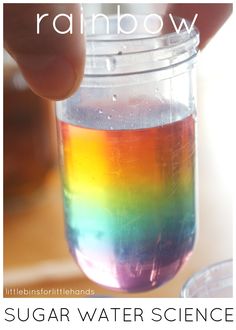 someone is holding a jar filled with colored liquid and the words rainbow in front of it