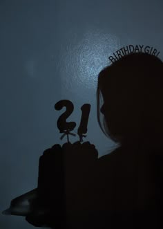 the silhouette of a woman holding a birthday cake