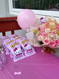 a pink table with hello kitty napkins and flowers on it next to a balloon