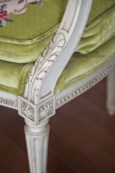 an ornate white chair with green upholstered cushions