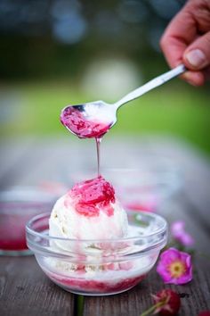 a spoon with some food in it on top of a glass bowl filled with ice cream