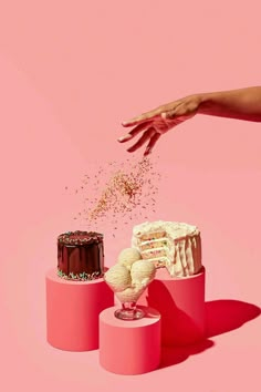 a hand reaching for a piece of cake with sprinkles coming out of it