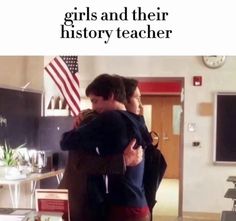 two young men hugging each other in a room with an american flag on the wall