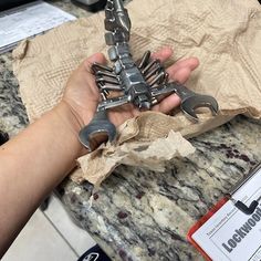 a person holding some kind of metal object in their hand on top of a table