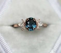 an engagement ring with a blue diamond surrounded by three white diamonds on a velvet pouch