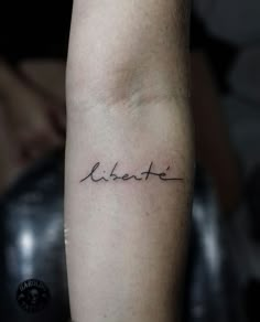 a person with a small tattoo on their arm that says, libertie in cursive writing