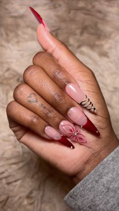 a woman's hand with red and pink nail polish on it